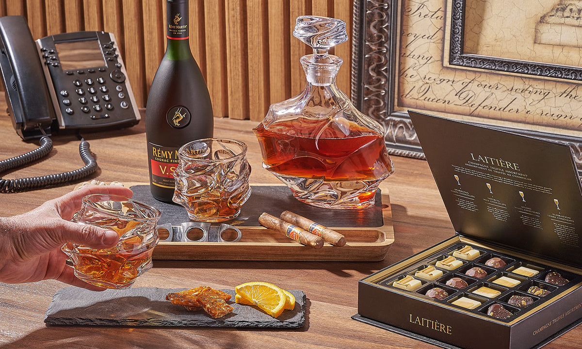 A sophisticated setup featuring cognac, cigars, and chocolates.