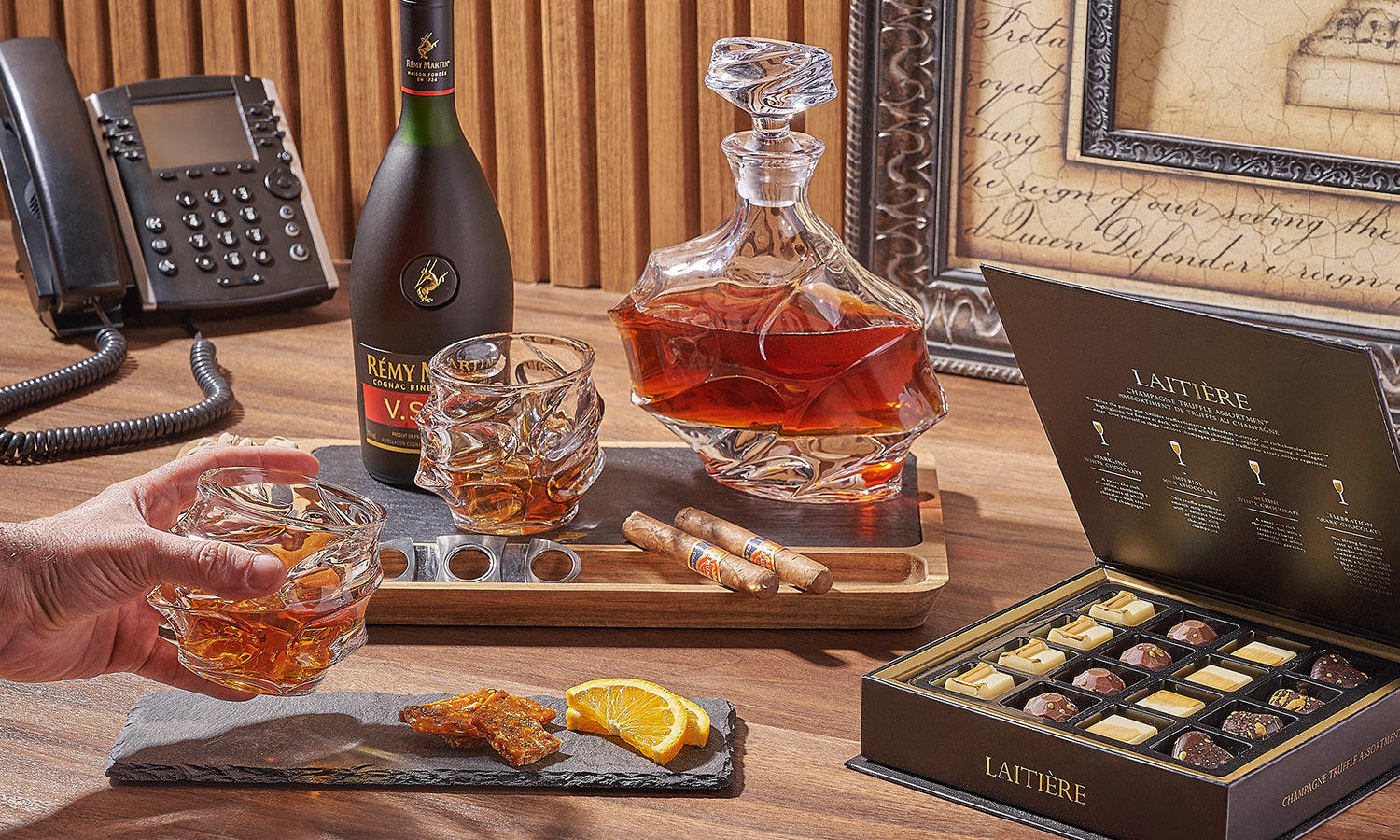 A sophisticated setup featuring cognac, cigars, and chocolates.